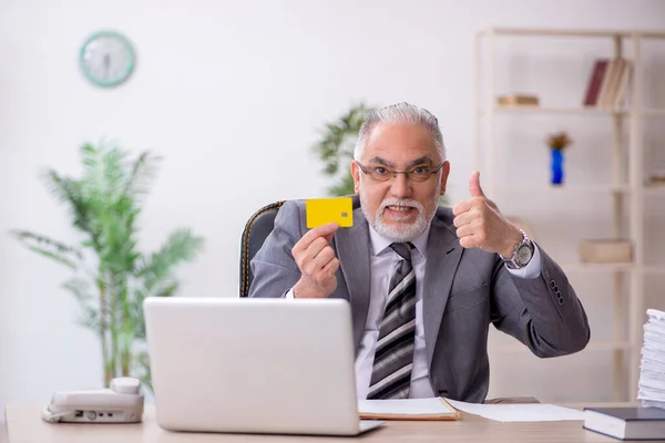 Ofiste kredi kartı tutan yaşlı bir erkek. — Stok fotoğraf