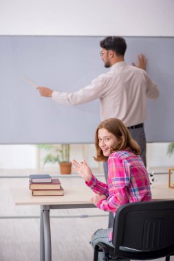 Sınıftaki genç erkek öğretmen ve kızıl saçlı kız.