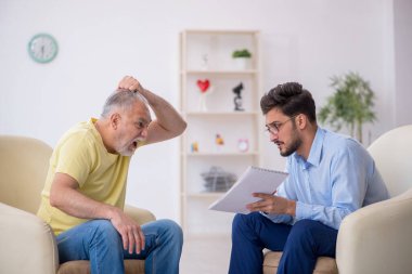 Yaşlı adam genç erkek psikoterapisti ziyaret ediyor.