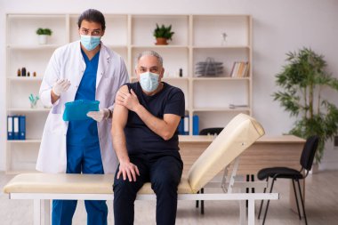 Yaşlı adam covid-19 aşı konseptinde genç doktoru ziyaret ediyor.
