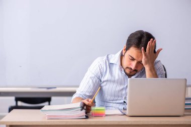 Genç erkek öğretmen beyaz tahtanın önünde.