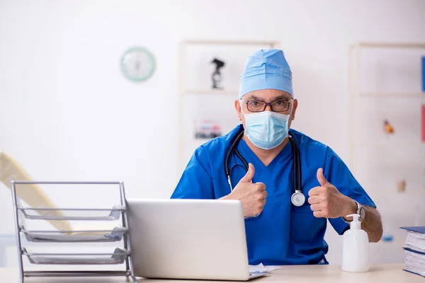 Viejo médico que trabaja en la clínica durante una pandemia — Foto de Stock