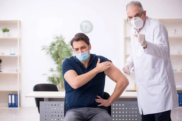 Junge männliche Patientin besucht alten Arzt im Impfpass — Stockfoto