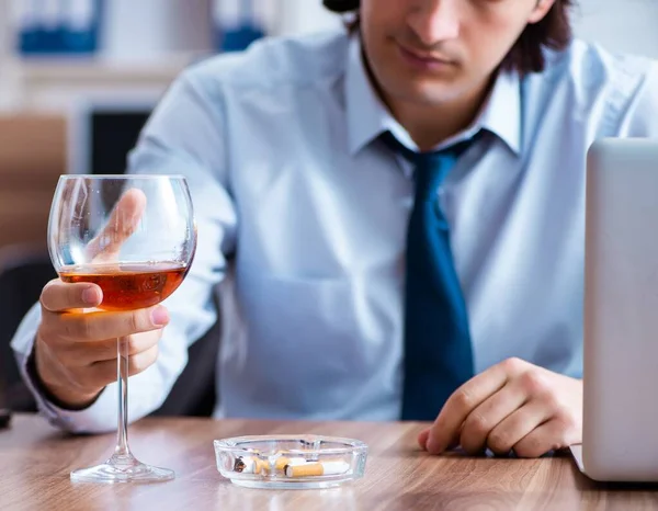 Male employee drinking alcohol and smoking cigarettes at workpla — Stock Photo, Image