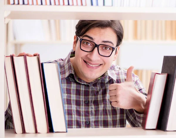 Jonge student op zoek naar boeken in universiteitsbibliotheek — Stockfoto