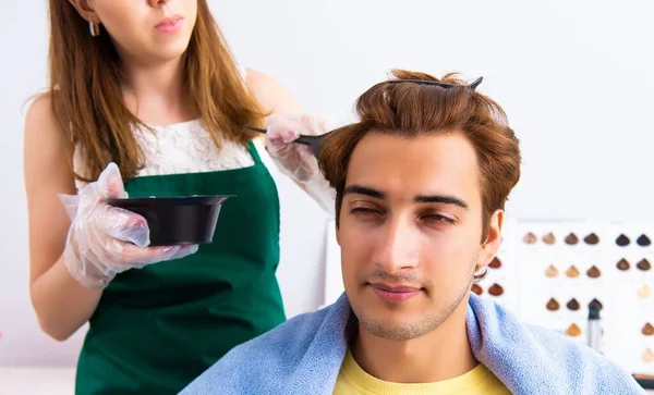 A mulher cabeleireira aplicando tintura ao cabelo do homem — Fotografia de Stock