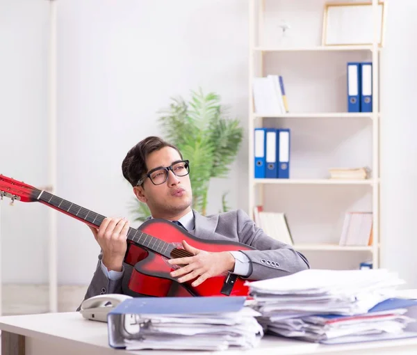 Mladý pohledný podnikatel hrající na kytaru v kanceláři — Stock fotografie