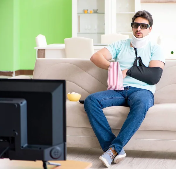목 과 팔에 부상을 입은 남자가 TV 를 보는 모습 — 스톡 사진