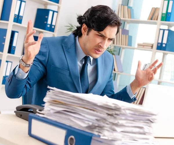 The young handsome male employee with too much work in the offic — Stock Photo, Image