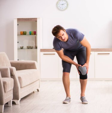 Evde iyileşen yaralı dizli genç adam.