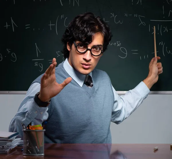Tahtanın önündeki genç matematik öğretmeni.