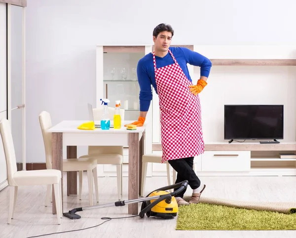 Молодой человек пылесосит свою квартиру — стоковое фото