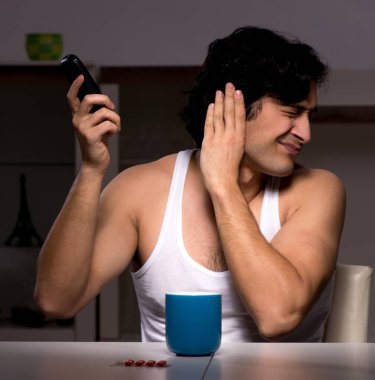 Genç adam gece evde acı çekiyor.