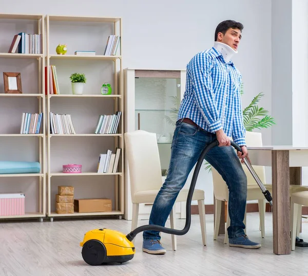 Injured man with neck injury vacuum cleaning house — Stock Photo, Image