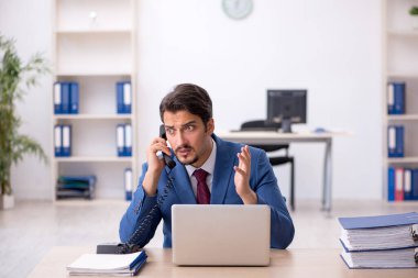 Ofisteki aşırı işten memnun olmayan genç bir erkek işçi.