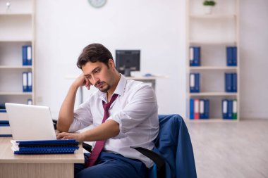 Ofisteki aşırı işten memnun olmayan genç bir erkek işçi.