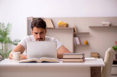 Genç erkek öğrenci salgın sırasında evde çalışıyor.