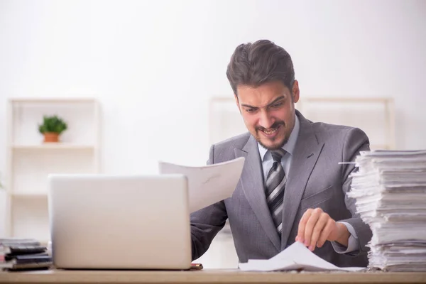 Jonge mannelijke werknemer ongelukkig met overmatig werk in het kantoor — Stockfoto