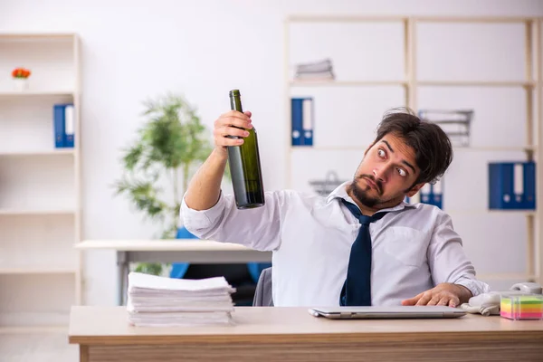 Empleado joven adicto al alcohol sentado en la oficina — Foto de Stock