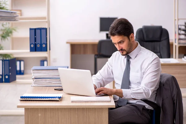 Young male employee and too much work in the office — Stock Photo, Image