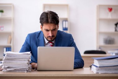 Genç bir erkek çalışan ve ofiste çok fazla iş var.