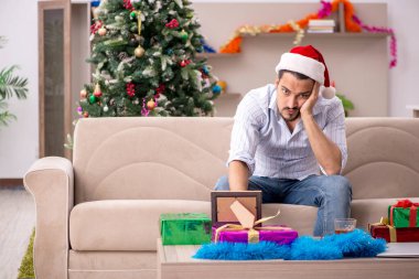 Genç adam Noel 'i evde yalnız kutluyor.