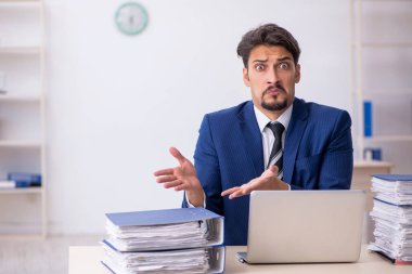 Genç bir erkek çalışan ve ofiste çok fazla iş var.