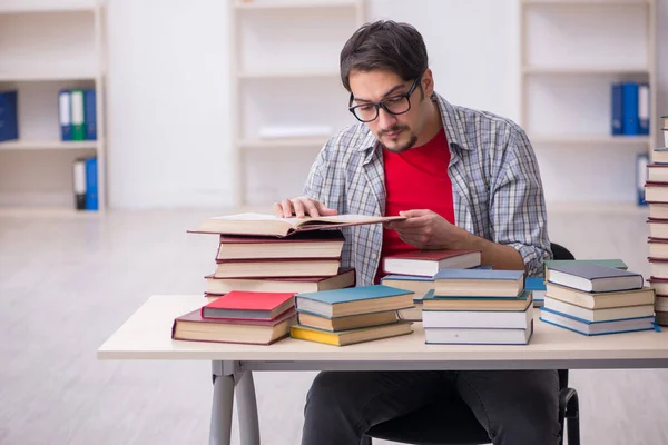 Genç bir erkek öğrenci ve sınıfta çok fazla kitap var. — Stok fotoğraf