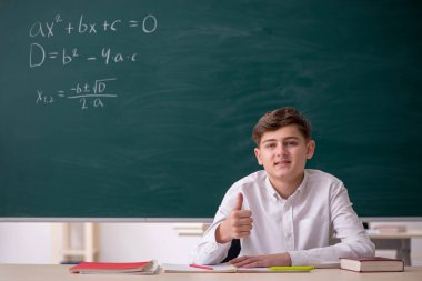 Okul çocuğu tahtanın önünde matematik çalışıyor.