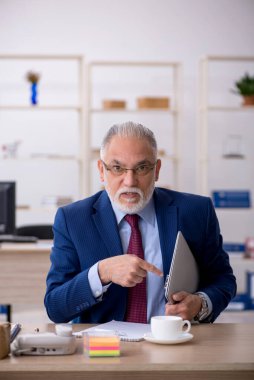 Ofiste çalışan yaşlı bir erkek.