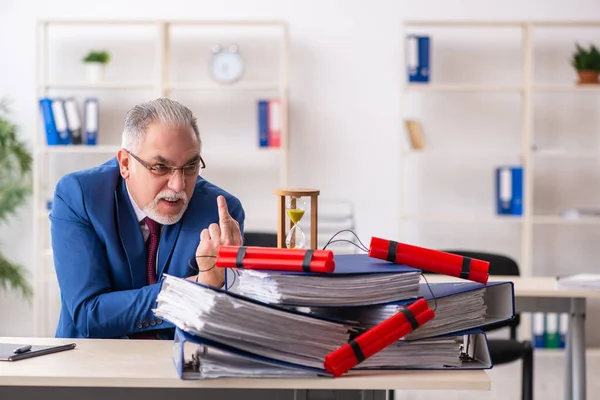 Old male employee with dynamite in the office — Stock Photo, Image