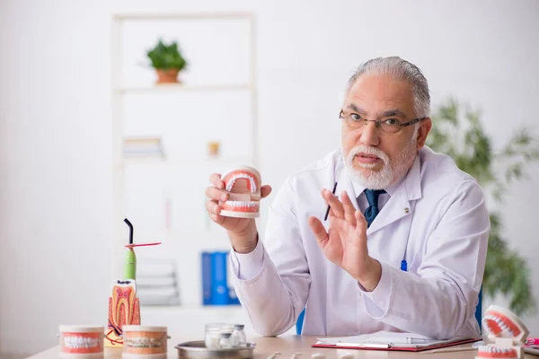 Oude mannelijke tandarts werkzaam in de kliniek — Stockfoto