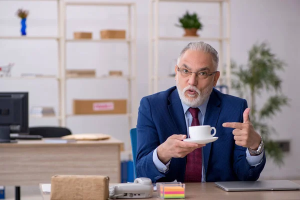 Velho funcionário do sexo masculino tomando café da manhã no escritório — Fotografia de Stock