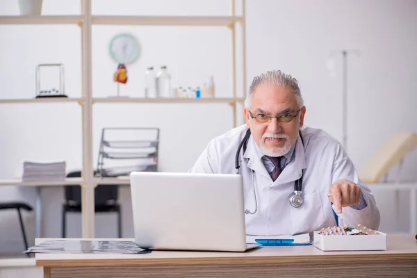 Старый врач-мужчина работает в клинике — стоковое фото