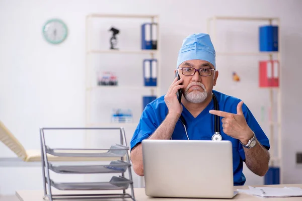 Oude mannelijke arts werkzaam in de kliniek — Stockfoto