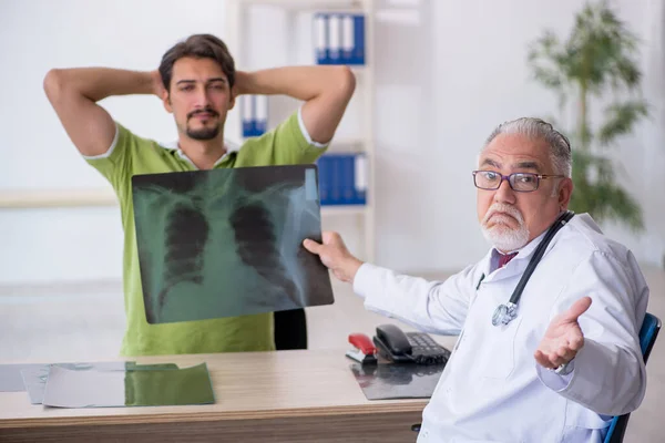 Jovem paciente masculino visitando velho médico radiologista masculino — Fotografia de Stock