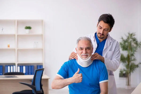 Vecchio collo ferito paziente maschile in visita giovane medico maschile — Foto Stock