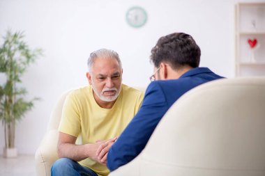 Yaşlı adam genç erkek psikoterapisti ziyaret ediyor.