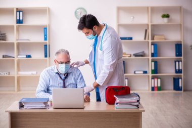 Genç erkek doktor, yaşlı işadamını iş yerinde ziyaret ediyor.