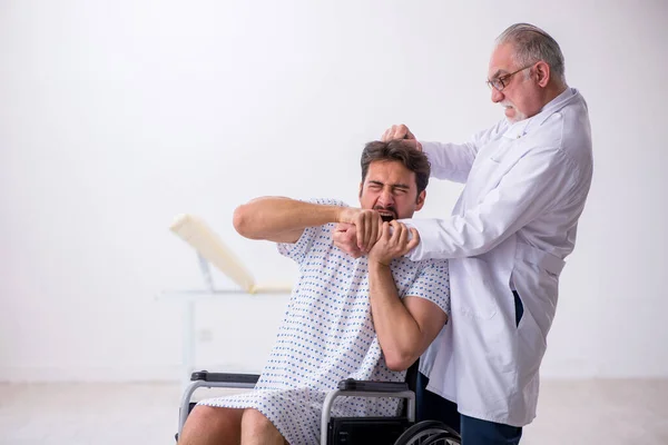 Old male doctor psychiatrist examining young disabled patient