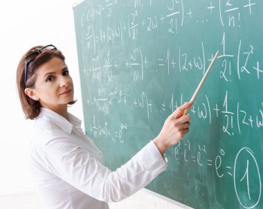 Karatahtanın önündeki kadın matematik öğretmeni.