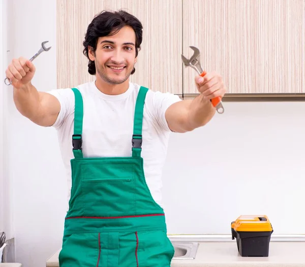 Mladý instalatér opravuje kohoutek v kuchyni — Stock fotografie