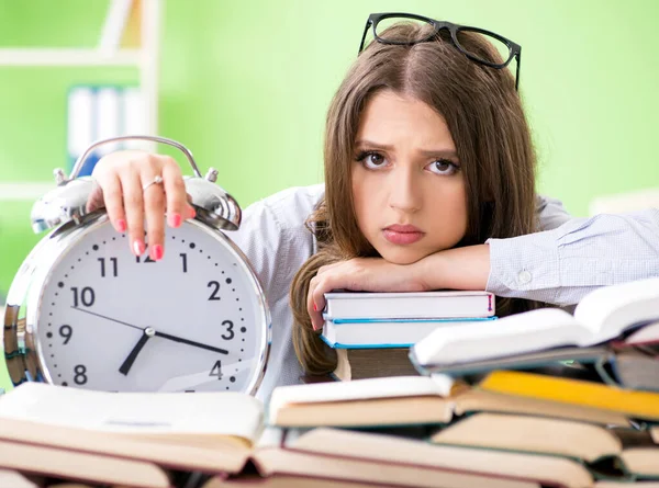 Jonge vrouwelijke student bereidt zich voor op examens met veel boeken in de tijd — Stockfoto