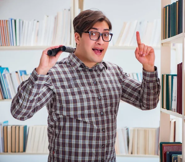 Giovane studente in cerca di libri nella biblioteca del college — Foto Stock