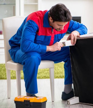 Müteahhit evde kırık mobilyaları tamir ediyor.