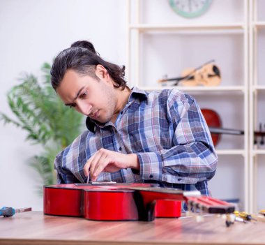 Gitarı tamir eden yakışıklı bir tamirci.