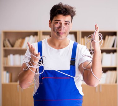 Kablolara dolanmış komik genç elektrikçi.