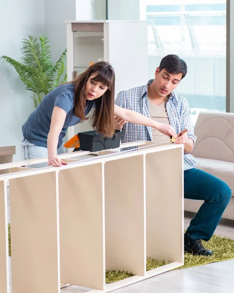 Young family assembling furniture at new house — Stock Photo, Image