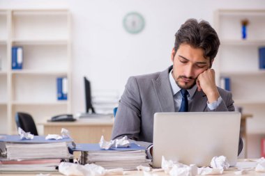 Genç bir erkek çalışan ve ofiste çok fazla iş var.