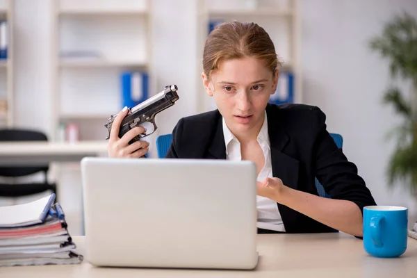 Young female employee holding gun in the office — Stock Photo, Image